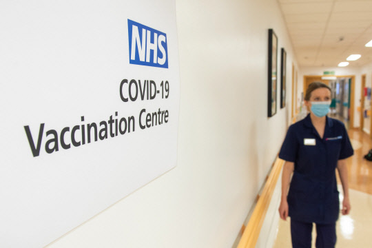 A nurse passes a sign indicating a Covid-19 Vaccination Centre at the Royal Free Hospital in London on December 7, 2020, ahead of the roll-out of the covid-19 vaccine tomorrow. - Britain has pre-ordered 40 million doses of the Pfizer-BioNTech vaccine in total, and is set to receive an initial batch of 800,000 to kickstart Tuesday's rollout. Elderly care home residents and their carers will be the very first in line, followed by those aged 80 and over and frontline health and care staff. (Photo by Dominic Lipinski / POOL / AFP)